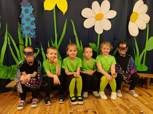 Zdjęcie przedstawia sześcioro dzieci siedzacych na scenie przebranych w stroje do występu