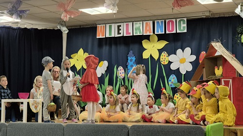 Zdjęcie przedstawia występujące na scenie dzieci z okazji uroczystości Wielkanocnej