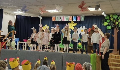 Zdjęcie przedstawia tańczącą na scenie grupę dzieci