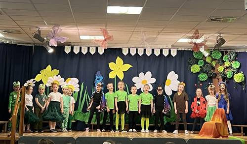 Zdjęcie przedstawia przebrane dzieci stojące na scenie biorące udział w przedstawieniu