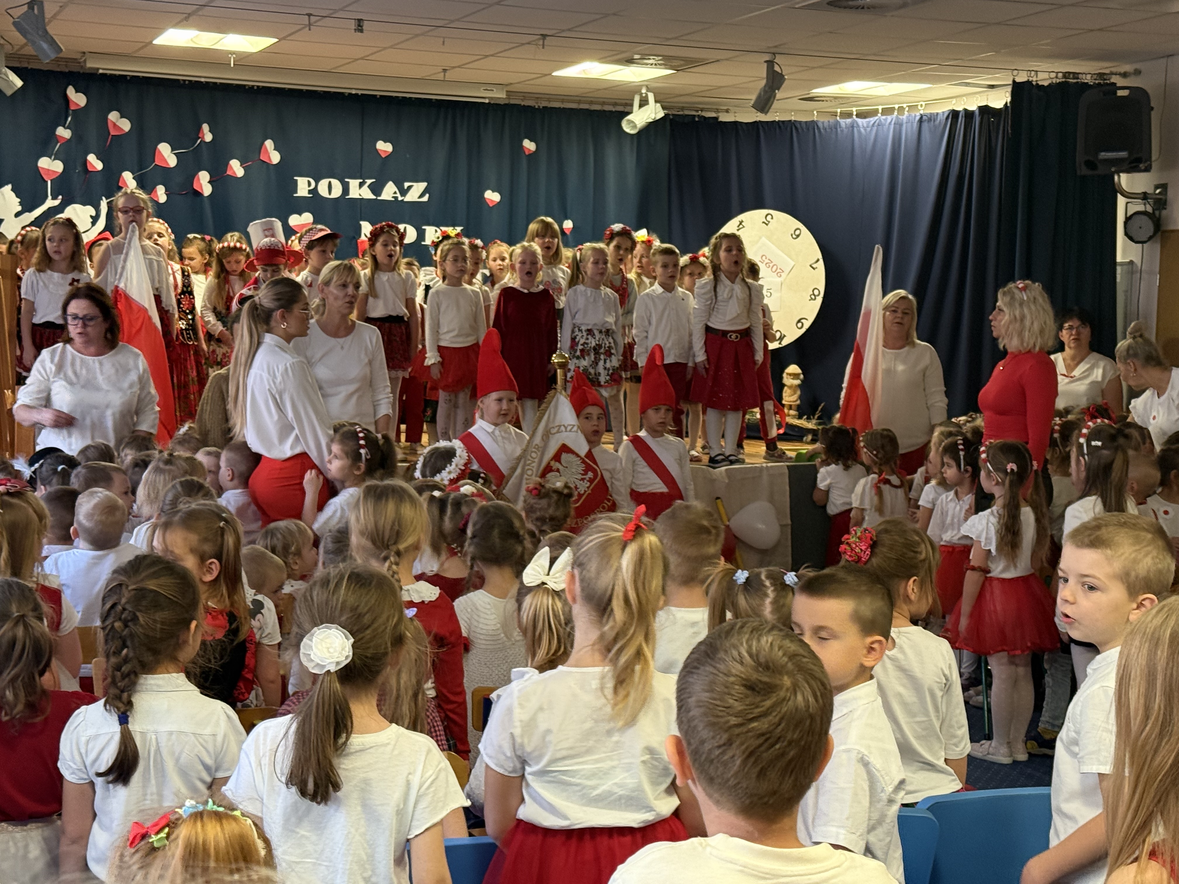 Zdjęcie przedstawia przedszkolaki oraz kadrę przedszkola podczas śpiewania hymnu państwowego